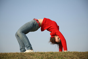 A woman is doing a handstand on a grassy field. Concept of freedom and strength, as the woman is...