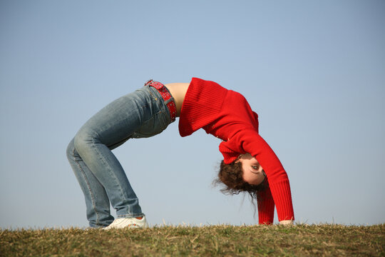A woman is doing a handstand on a grassy field. Concept of freedom and strength, as the woman is able to balance herself in a challenging position