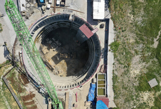 Aerial view of a deep excavation site with heavy machinery and construction equipment, creating a stark contrast against the surrounding green landscape, Istanbul, İstanbul, Turkey.
