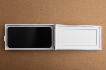 Minimalist open smartphone box on cardboard background