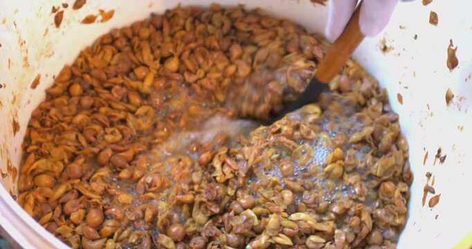 A man mixes homemade grape pulp for fermentation in a bucket.