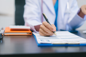 Fototapeta premium Asian female doctor using laptop for teleconsultation and checking patient's EHR record, wearing glasses,demonstrating modern healthcare,online medical services professional expertise in hospital