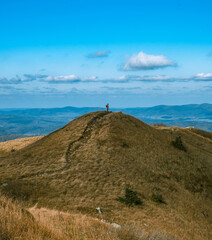 A man stands on a hilltop in an autumnal setting. The Polish Bieszczady Mountains. © Tomasz