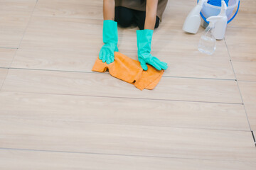 An Asian woman housekeeper wearing gloves and an apron is cleaning a modern office or home. She works diligently, maintaining hygiene and order as part of professional cleaning service