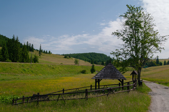 View of the wooden shelter beside a path through the meadow beneath the Low Tatras mountains, Source of Hron river, Banskobystricky kraj, Slovakia.