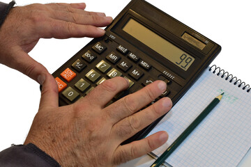 A man is working on a calculator, with a notepad and pencil lying nearby.