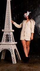 Beautiful girl in a mask holding Eiffel Tower