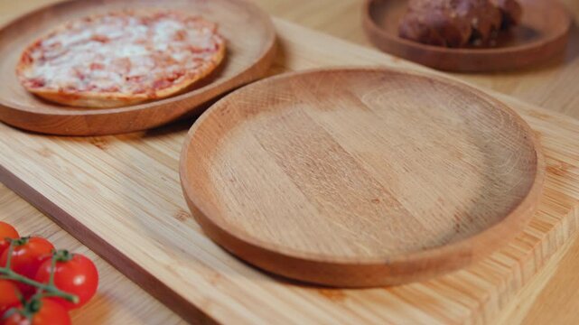 Empty Wooden Plates On Bamboo Board With Cherry Tomatoes And Pizza In Background Ready For Plating And Service . Media