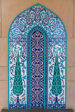 View of intricate blue and white mosaic tilework, featuring floral patterns and symmetrical designs, stands out against a neutral wall, Muscat, Muscat Governorate, Oman.