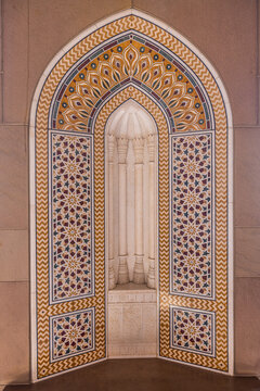 View of an ornate Mihrab with a cream interior and decorative floral patterns, framed by a golden border, Muscat, Muscat Governorate, Oman.