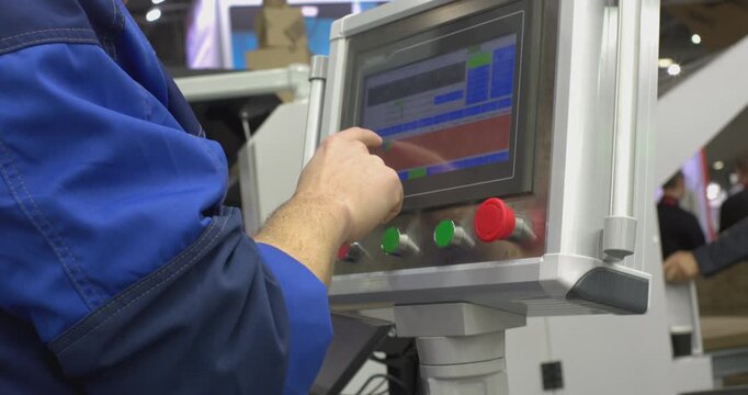 Factory worker operating industrial machine touchscreen control panel