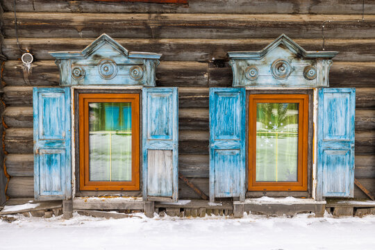 Fototapeta View of intricate blue window frames against the rustic, weathered log cabin, peeking through the glass in Irkutsk, Irkutsk Oblast, Russia.