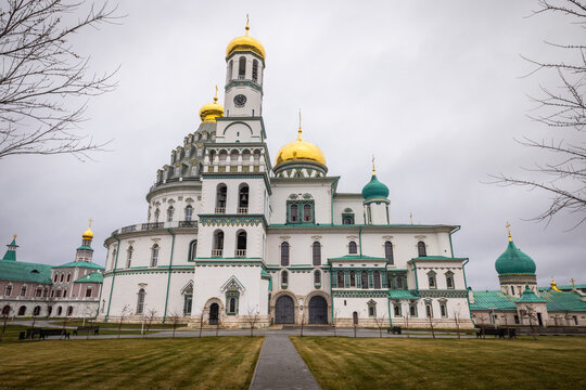 View of the New Jerusalem Monastery stands majestically under a cloudy sky, gold domes gleaming, green roofs complementing the muted landscape, Istra, Moskovskaya oblast', Russia.