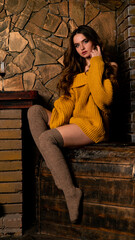 Beautiful girl sitting next to the fireplace. Luxury interior decorated for Christmas with fir branches and toys