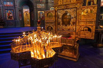 View of golden icons gleaming in the soft light of flickering candles, illuminating the ornate interior of a Russian Orthodox church, Kubinka, Moscow Oblast, Russia.