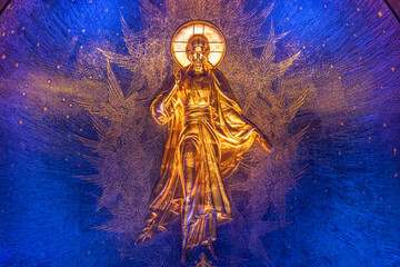 View of a radiant golden figure, bathed in ethereal light against a deep blue backdrop in an indoor space, Kubinka, Moscow Oblast, Russia.
