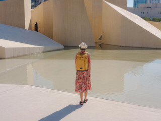 Young woman exploring Qasr Al Hosn Park in Abu Dhabi. Surrounded by lush greenery and historical landmarks, she enjoys the serene atmosphere and Emirati heritage in heart of city.