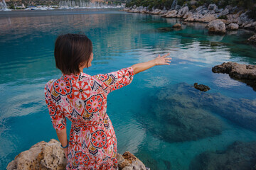 Woman stands on Mediterranean Sea coast, embracing cool, off-season atmosphere with waves crashing on shore and overcast sky above. serene, peaceful moment on quiet beach.