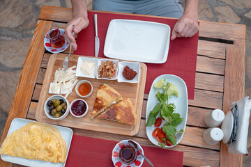 Traditional Turkish breakfast spread with fresh bread, olives, cheese, tomatoes, cucumbers, and variety of jams and spreads. Enjoyed in vibrant setting, capturing essence of Turkish morning culture.