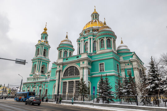 View of a stunning turquoise cathedral with gleaming golden domes rises majestically against a muted sky, snowy ground, Moskva, Moskva, Russia.