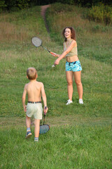 A young girl is playing tennis with a boy. The girl is wearing a blue and white striped shirt and...