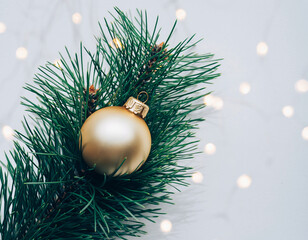 Golden Christmas Ornament Hanging on Lush Green Pine Branches Against a Clean White Background in Minimalist Holiday Still Life Photography