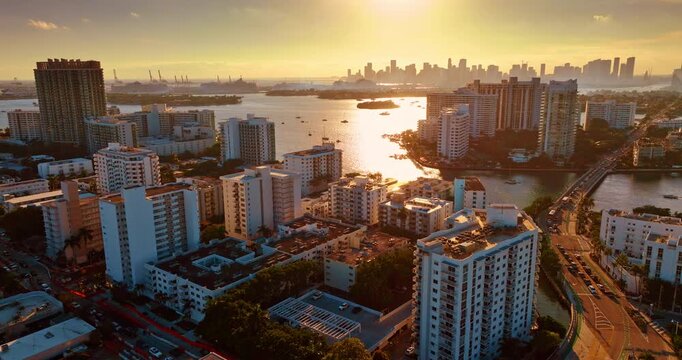 Scenery of Miami, Florida dazzled by the light of setting sun. Approaching Biscayne Bay with Brickel Key islands and high-rise skyline silhouette at backdrop.