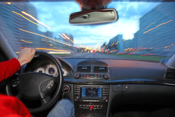 Fototapeta premium A person is driving a car with the windows down and the radio on. The car is moving quickly down a city street