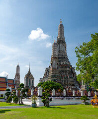 Detailed view of the ornate towers of Wat Arun in Bangkok, Thailand, showcasing rich ceramic floral patterns, sculpted figures, and intricate decorations under bright daylight.