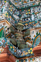 Detailed view of the ornate towers of Wat Arun in Bangkok, Thailand, showcasing rich ceramic floral patterns, sculpted figures, and intricate decorations under bright daylight.