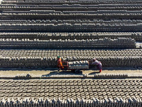 Narayanganj, Bangladesh - 09 November 2024: Aerial view of neatly stacked rows of bricks, awaiting their transformation, stretch across the landscape, a testament to human industry.