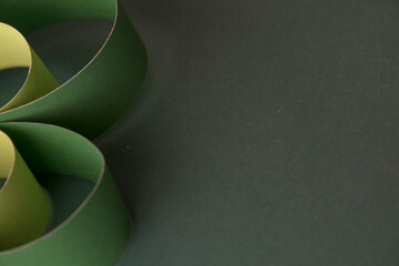 Extreme close-up of a large, smooth green paper strip curving along the left edge, leaving the dark...