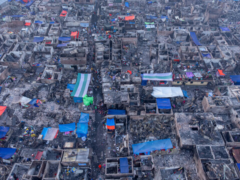 Dhaka, Bangladesh - 28 November 2025: Aerial view of the aftermath reveals a stark landscape of charred buildings and scattered debris, punctuated by vibrant tarps amidst the ruins.