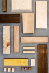 Flat lay of various wood and plywood pieces on concrete texture. Carpentry background.