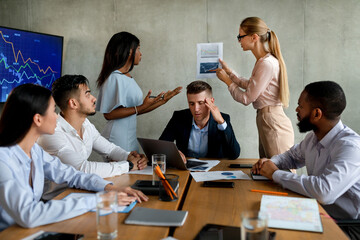 Fototapeta premium A diverse business team is experiencing communication problems during a meeting in the office. Members are arguing while discussing company strategy and looking for solutions.