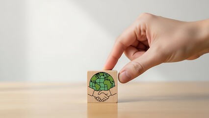 A person placing their finger on a small wooden block with a green design on a light brown surface indoors