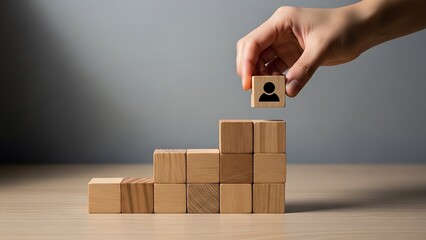 A hand placing a person block on top of growing wooden blocks