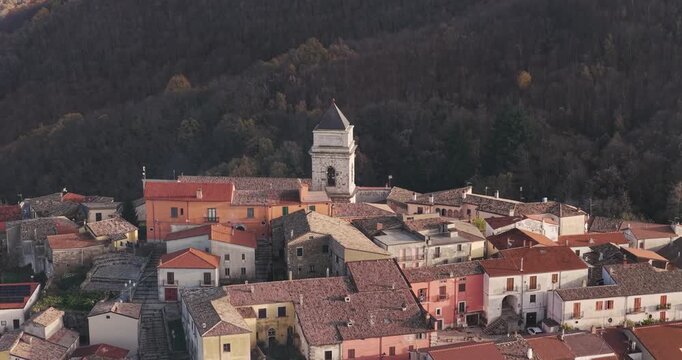 Aerial view of the closely packed buildings with terracotta roofs, dominated by a single tower, nestled near a dense forest, Guardia Lombardi, Irpinia, Italy.