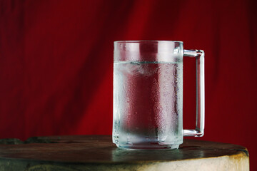 Chilled Glass Mug of Iced Water with Condensation on Red Background