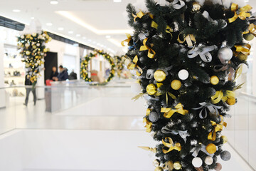 Christmas decorations featuring vibrant ornaments and ribbons adorn a shopping center, creating a...