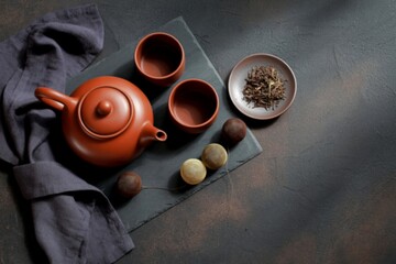 Clay teapot and cups with tea leaves and macarons