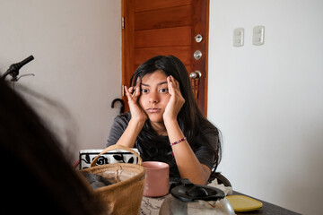 A teen is sitting at a table with a cup in front of her