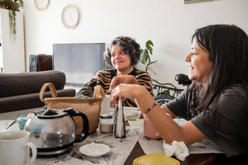Mother and daughter are sitting at a table, one of them is wearing a striped shirt