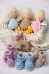 Handmade crochet baby toys set featuring three cute sleeping angel dolls, a small crocheted rocking horse, and knitted baby booties in pastel colors.