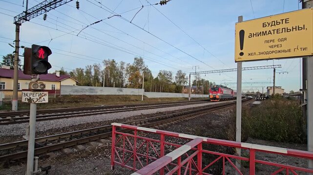 SHARYA - SEP 26, 2024: Red traffic light is lit up at a railroad crossing, warning drivers to stop. A sign is posted on the side of the tracks, in Russian