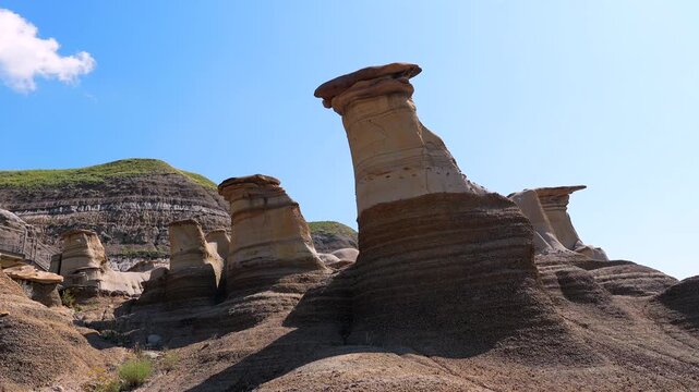 Sunlight illuminates the unique hoodoo rock formations in drumheller valley, casting changing shadows throughout the day, showcasing the geological wonders of the canadian badlands