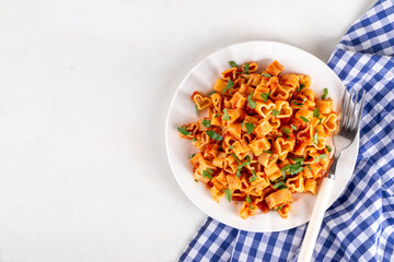 Heart shaped pasta with tomato sauce. Classic italian marinara or bolognese pasta with fresh herbs, simple and delicious recipe for Valentine day or date night, on white table copy space