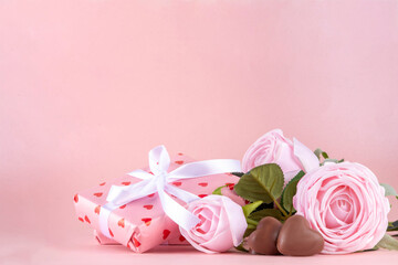 Valentine day, February 14 holiday background with pink roses flowers bouquet, gift boxes and heart-shaped chocolates on pastel colored pink background copy space