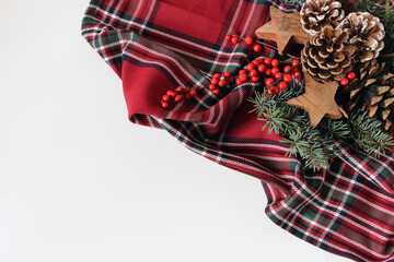 Christmas flat lay still life. Red tartan fabric, pine cones, fir tree branches. Wooden stars, holly berries isolated on white background. Festive holiday decoration Winter season styling, rustic Xmas