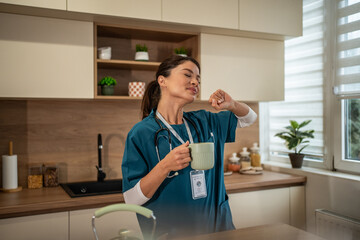 Healthcare worker stretching and drinking coffee in kitchen